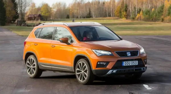 Orange Seat Ateca på en grusväg, redo för ett test. En förare sitter bakom ratten.