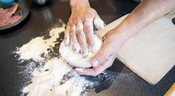 Händer som knådar deg med mjöl för en äkta neapel pizza.