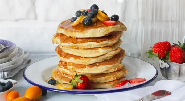 Pancake perfetti, dorati e soffici, pronti per essere gustati. Ecco come fare i pancake per una colazione da campioni, guarniti con frutti di bosco e sciroppo.