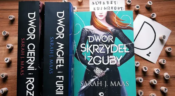 Książki z serii "Dwór cierni i róż" Sarah J. Maas. Tom 6 "Dwór skrzydeł i zguby" z piękną okładką.