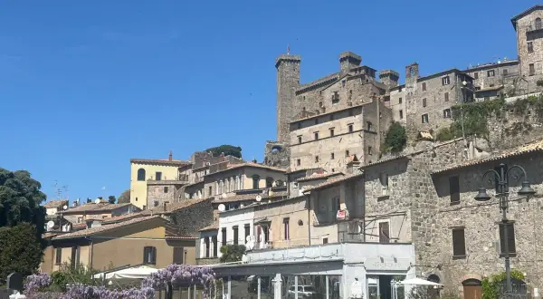 Borgo medievale sul lago di Bolsena, cosa vedere: un castello imponente, case in pietra e un ristorante fiorito.