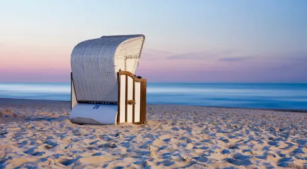 Pusta plaża o zachodzie słońca, idealna na tanie miejscowości nad morzem. Wygodny kosz plażowy czeka na turystów.