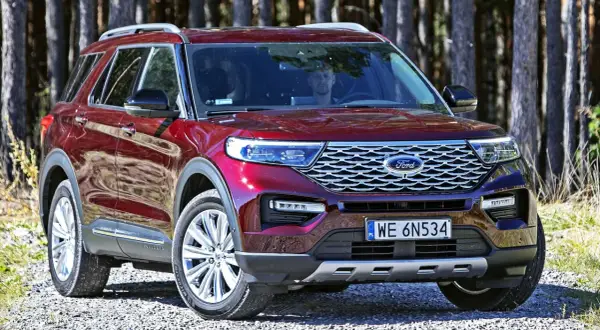 Czerwony Ford Explorer, jeden z wielu modeli tej marki, zaparkowany na leśnej drodze.
