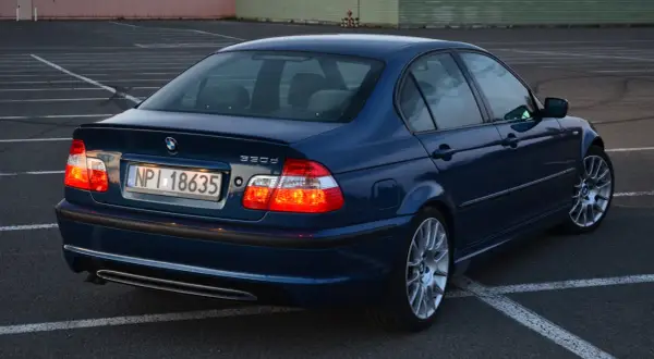 Granatowe BMW E46 330d na parkingu. Wiele pozytywnych opinii o tym modelu, szczególnie o jego silniku.