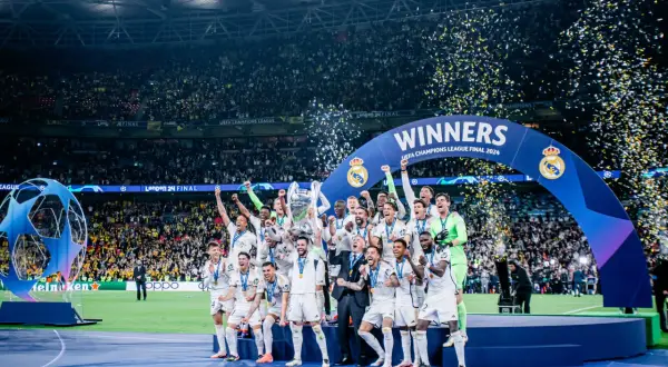 Piłkarze Realu Madryt świętują zwycięstwo w Lidze Mistrzów 2024, podnosząc trofeum wśród konfetti.