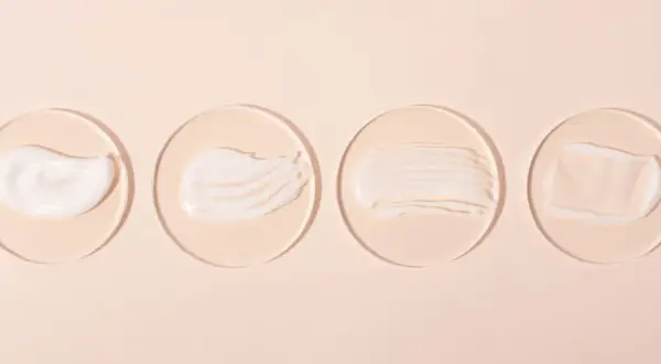 Vier Cremeproben auf Glasplättchen: eine reichhaltige, eine seidige, eine gestreifte und eine transparente. Ideal für Hautpflege mit niacinamide und vitamin c.