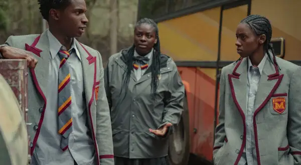 Kedar Williams Stirling i dwaj koledzy w szkolnych mundurkach stoją obok autobusu.