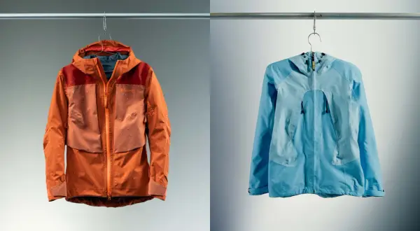 Deux vestes, une orange et une bleue, suspendues. La veste orange est mouillée, montrant l'efficacité du Gore-Tex.