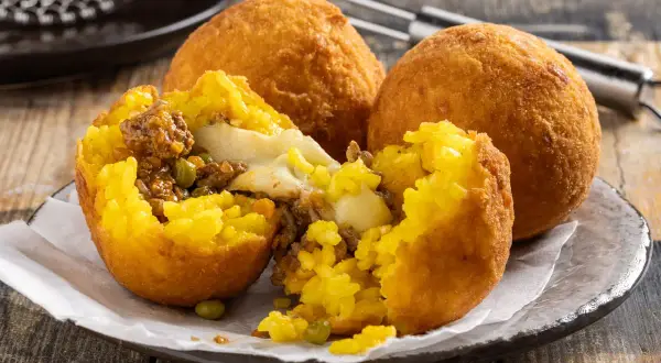 Arancini ripieni di carne e formaggio filante, un esempio di come si fanno gli arancini siciliani, dorati e croccanti.