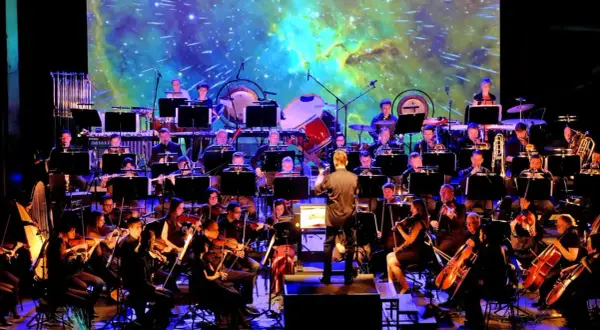Orkiestra symfoniczna wykonuje najlepszą muzykę filmową wszech czasów na tle kosmicznej projekcji.