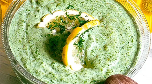En skål med krämig salsa verde, garnerad med citronskivor och dill. Perfekt till sommarmaten!