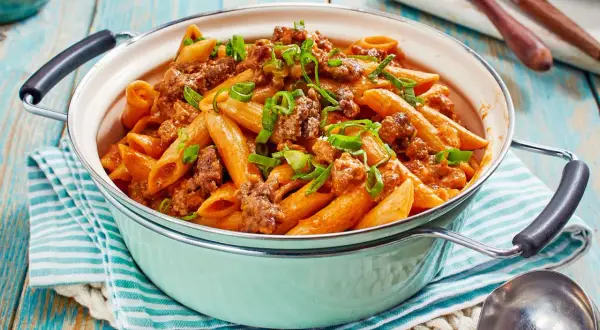 Herzhaftes One Pot Pasta mit Hackfleisch und einer cremigen Tomatensoße, garniert mit Frühlingszwiebeln.