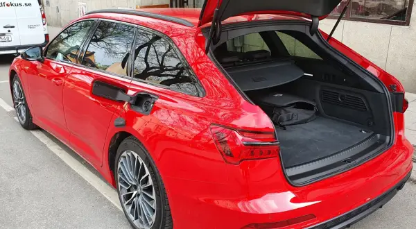 Röd Audi A6 Avant med öppet bagageutrymme. En svart väska ligger i det rymliga audi a6 bagageutrymmet.