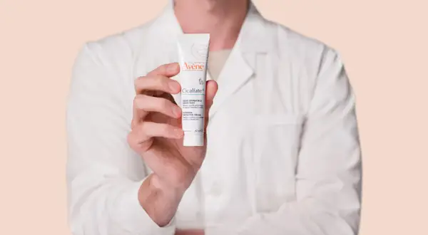 Mano sosteniendo un tubo de crema Avène Cicalfate+, ideal para piel irritada.