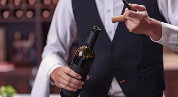 Un sommelier mostra come usare cavatappi per aprire una bottiglia di vino.