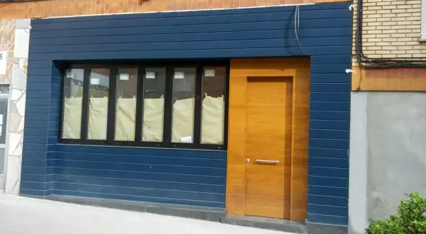 Fachadas de locales convertidos en viviendas, con puerta de madera y ventanas cubiertas.
