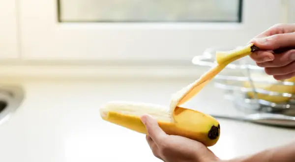 Dłoń obiera banana. Pamiętaj, z czym nie łączyć potasu, by uniknąć problemów zdrowotnych.