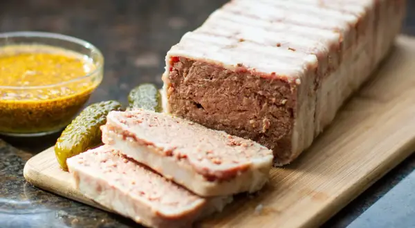 Pyszny pasztet zawinięty w boczek, pokrojony na plastry, z ogórkami i musztardą. Idealny na kanapki, zastanawiasz się, ile pieczemy pasztet?