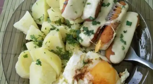 Talerz z ziemniakami, jajkiem sadzonym i paluszkami rybnymi w serze.