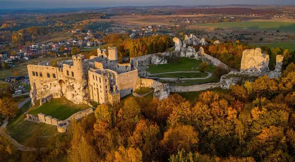 Ruiny zamku na Szlaku Orlich Gniazd, idealne na wycieczkę samochodem. Jesienne barwy drzew otaczają malowniczą trasę.