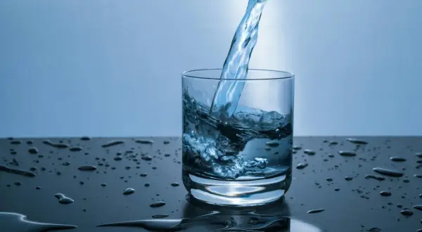 Verre d'eau versé, éclaboussures sur la table. L'eau calcaire peut causer du mal de ventre.