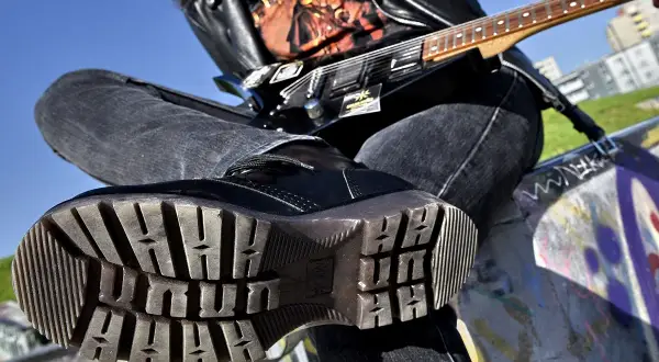 Czarna, błyszcząca glan, dżinsy i gitara elektryczna – kwintesencja stylu grunge.