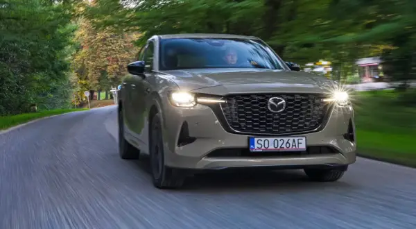 Nowa Mazda CX-60 3.3 diesel sunie po krętej drodze wśród zieleni.