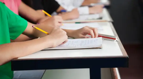 Schüler schreiben in ihren Heften. Ein Bleistift liegt bereit, um die Fortschritte im formative assessment festzuhalten.