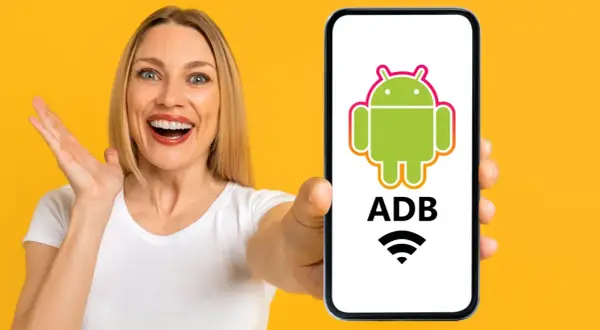 Mujer sorprendida muestra un teléfono con el logo de Android y "ADB" escrito, indicando control remoto.