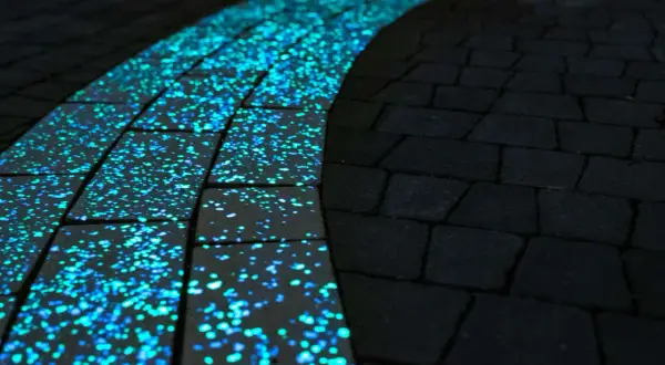 Ścieżka z luminescencyjnej kostki wokół pomnika, nocą mieniąca się błękitno-zielonym blaskiem.
