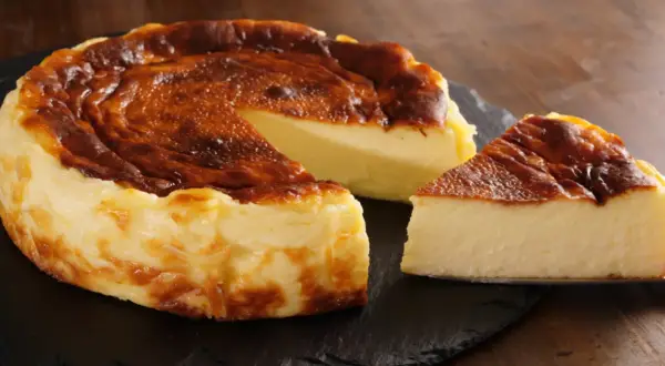 Pyszny, lekko przypieczony sernik na czarnej desce. Nawet jeśli sernik kcal kusi, warto spróbować!