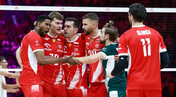 Drużyna Polski w siatkówce świętuje sukces w Lidze Narodów. Zawodnicy w czerwonych strojach z orłem na piersiach cieszą się po wygranej.