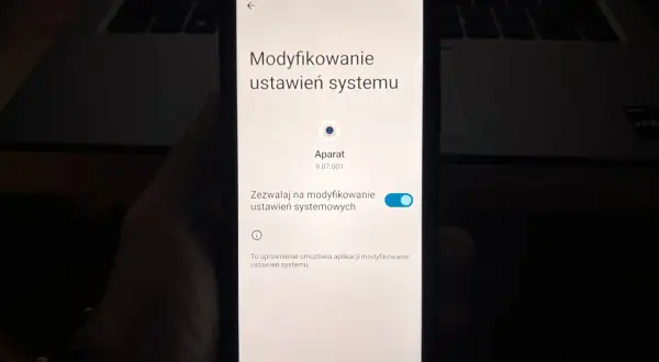 Ekran telefonu pokazuje ustawienia systemu, gdzie można sprawdzić, jak włączyć kamerę w telefonie.