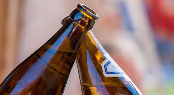Dwie butelki z alkoholem w zielonej butelce zbliżają się do toastu.