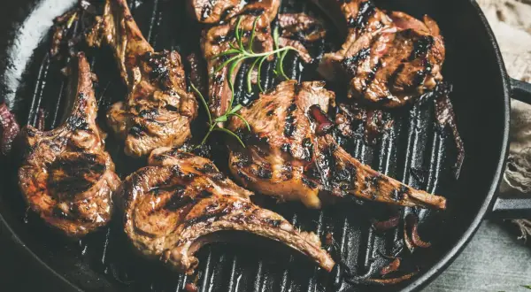 Saftiges Lamm grillen in einer Pfanne mit Rosmarin und Zwiebeln. Perfekt gegrillte Lammkoteletts mit köstlichen Röstaromen.
