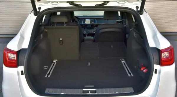 Otwarty bagażnik białej Kia Optima kombi. Wnętrze jest puste, gotowe na podróż.