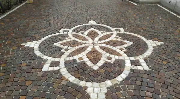 Vicolo carrabile in porfido con un elegante motivo floreale centrale.