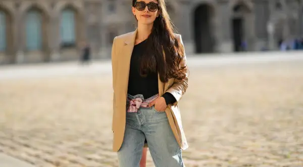 Stylowa kobieta w beżowej marynarce i jeansach mom fit. Jej stylizacje to kwintesencja miejskiego szyku.