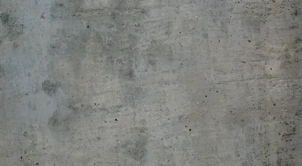 Szara, chropowata powierzchnia betonu z widocznymi nierównościami i śladami po szalunku.