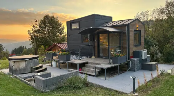 Tiny house dans le Jura, avec jacuzzi et mobilier extérieur, au coucher du soleil.