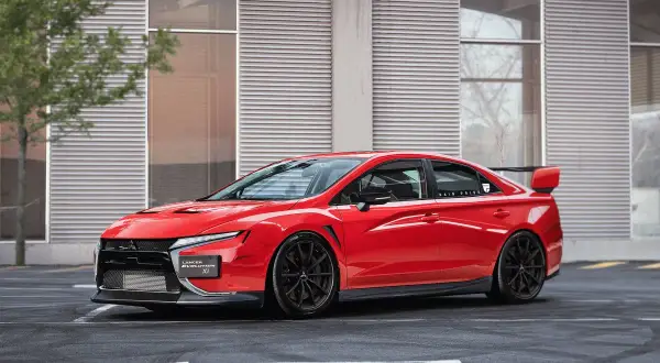 Czerwony Mitsubishi Lancer Evolution XI z czarnymi felgami i spoilerem, zaparkowany przed nowoczesnym budynkiem.