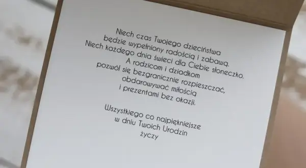 Wiersz z życzeniami "100 lat wszystkiego najlepszego z okazji urodzin" na kartce z brązowej tektury.
