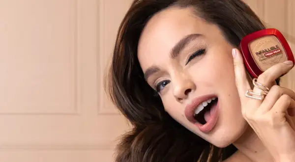 Uśmiechnięta kobieta prezentuje puder L'Oréal Infallible 24H Fresh Wear.