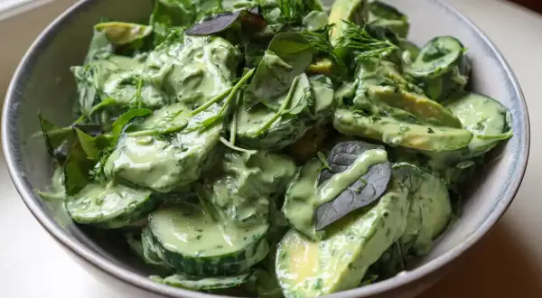 En krämig green goddess sallad med avokado, gurka och färska örter i en skål.