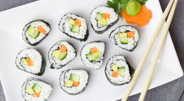 Talerz sushi z awokado, ogórkiem i marchewką. Czy sushi jest kaloryczne? Zależy od składników, ale te warzywne rolki wyglądają lekko!