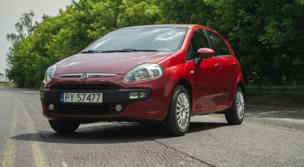 Czerwony Fiat Grande Punto na tle zieleni.