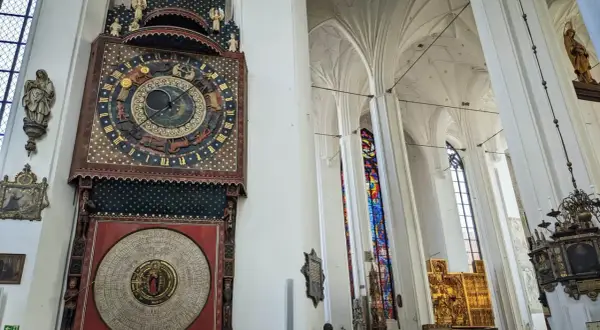 Wnętrze Bazyliki Mariackiej w Gdańsku. Imponujący zegar astronomiczny i witraże zachwycają podczas zwiedzania.