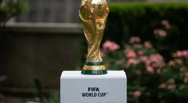 Złoty Puchar Świata FIFA, marzenie każdego z gospodarzy mistrzostw świata w piłce nożnej, lśni na tle zieleni i różowych kwiatów.