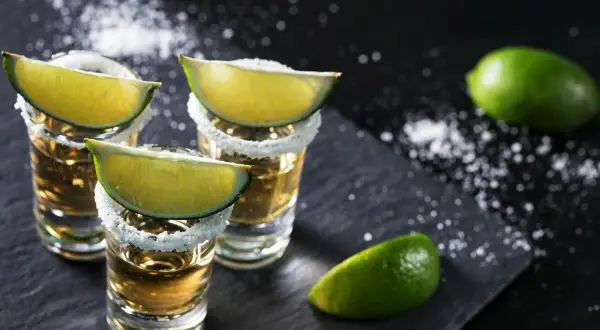 Trzy kieliszki tequili z solą i limonką, gotowe do degustacji. Idealne na wieczór z przyjaciółmi, jak ten z piosenką "Chantre".