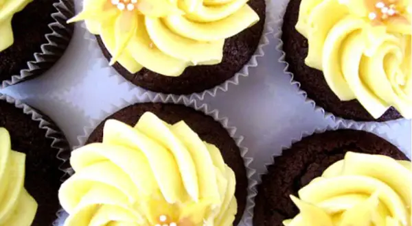 Chokladmuffins med gul frosting och blomsterdekoration. En härlig syn av frosting muffins som ser aptitliga ut.
